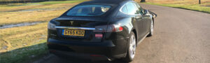 black tesla s driving in countryside